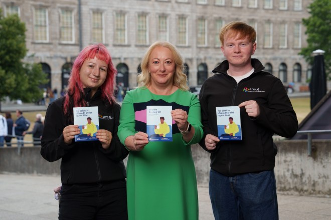 Woman with pink hair, woman in green dress and man in black jumper holding Guide to Student Renting booklets